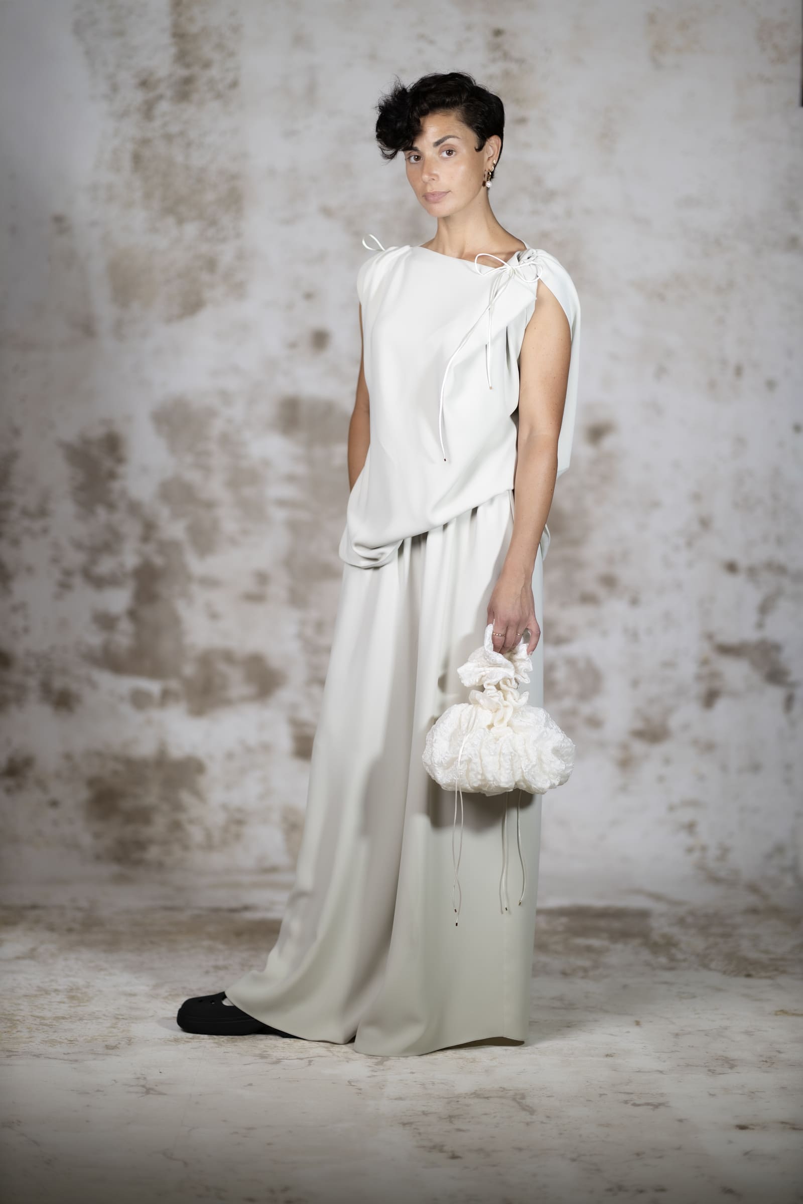 Full-body shot of a model wearing the Pedra blouse, a loose minimalist crepe top with a fluid draped silhouette and elegant rat-tail ties - Anabel Santos