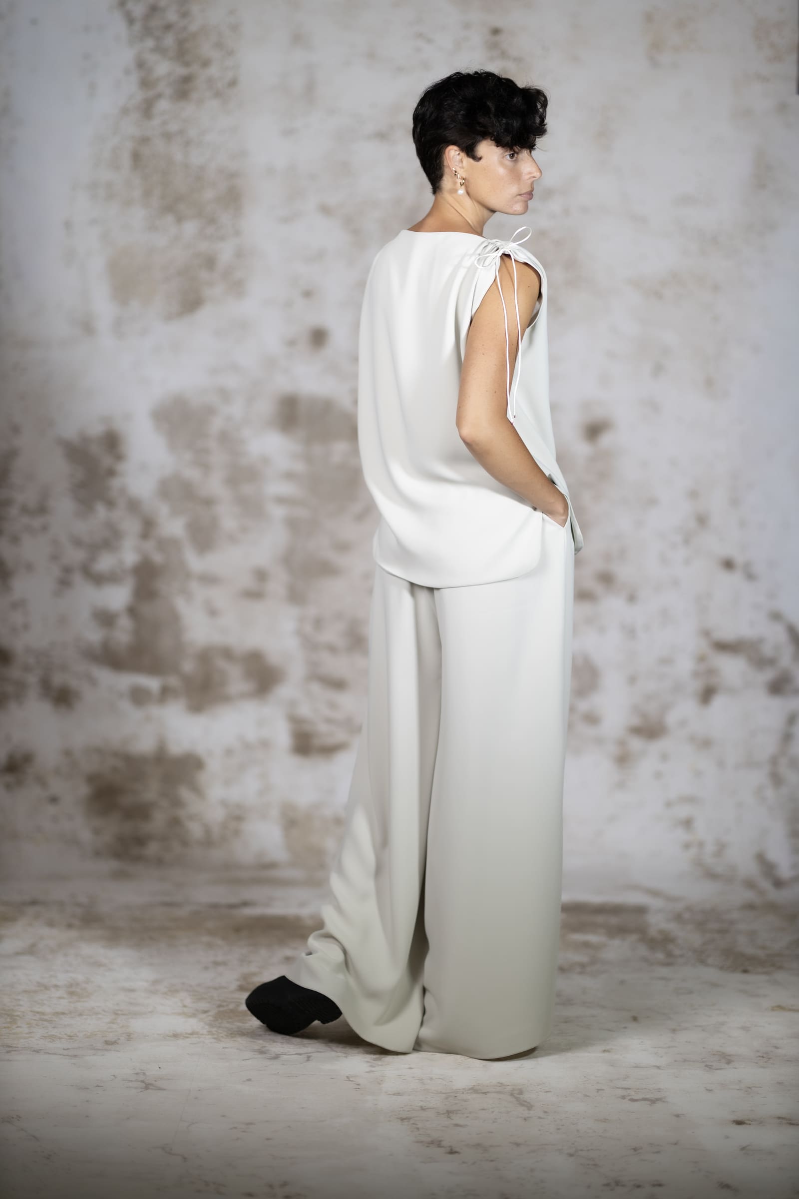 Full-body back view of the Pedra blouse, showing the elegant clean drape of the minimalist crepe fabric and handcrafted rat-tail tie details - Anabel Santos